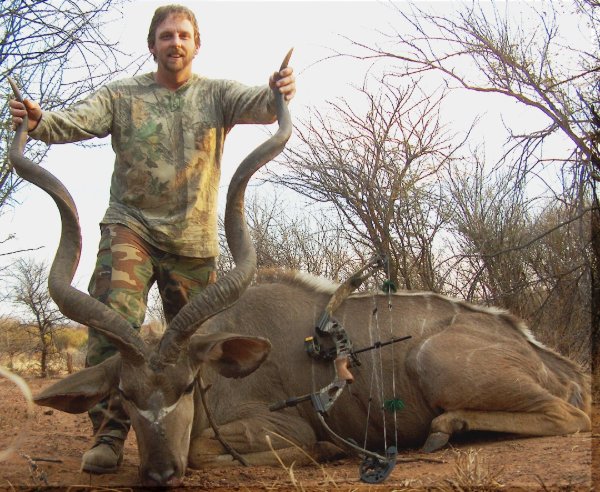 Bow hunter posing with a large kudu antelope trophy in the African bush