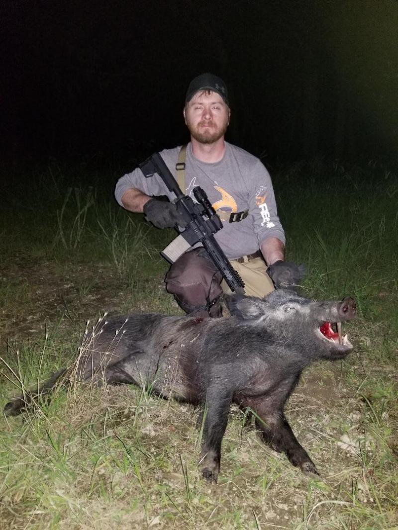 Hunter and Rifle with Big Adult Wild Hog Harvested on a Hog Hunting Trip in Oklahoma